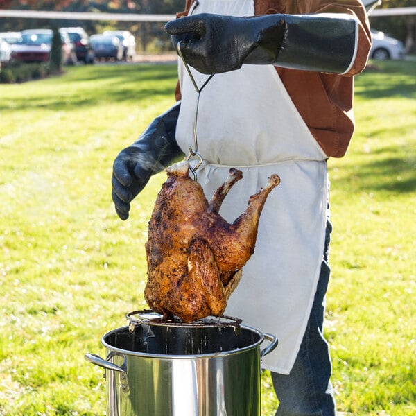 pulling a deep fried turkey out of a turkey fryer